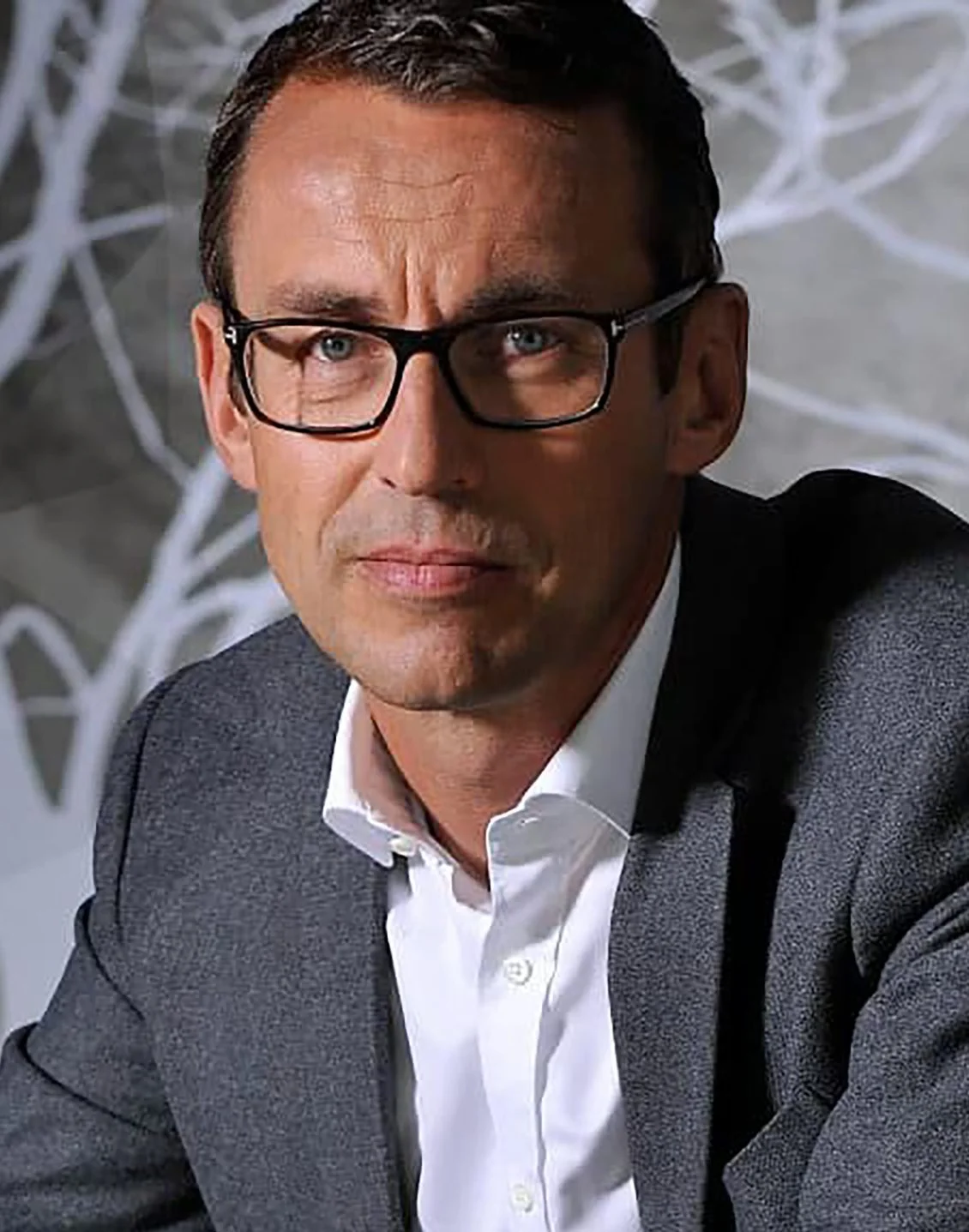 Porträt eines Mannes mit Brille und grauer Jacke