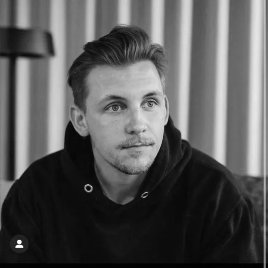 Porträt eines Mannes mit kurz geschnittenen Haaren und Bart, der nachdenklich in die Kamera schaut.